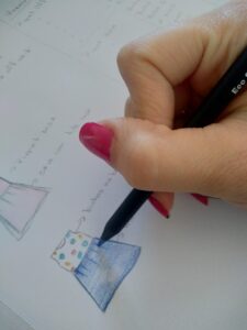 mão de mulher desenhando um vestido infantil