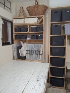 oficina de costura com mesa de madeira e prateleiras com pastas e caixas